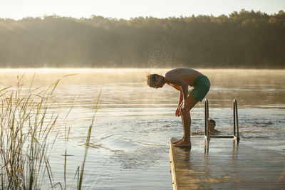 Side view of person on rock by lake