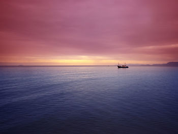 Boat on sea against cloudy sky during sunset