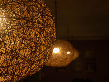 Close-up of illuminated light bulb hanging from ceiling