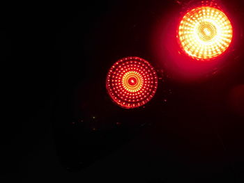 Low angle view of illuminated lighting equipment against black background