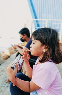 Girl playing with people sitting outdoors