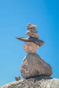 Low angle view of stone stack against blue sky