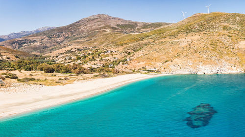 Scenic view of sea and mountains against blue sky