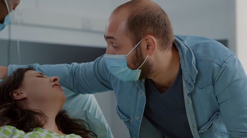 Husband wearing mask consoling pregnant wife