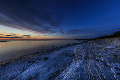 Scenic view of beach against sky at sunset