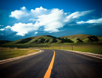 Empty road along landscape against sky