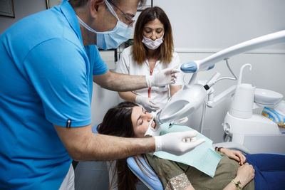 Male dentist examining female patient in clinic