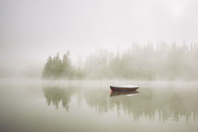 Boat in lake against sky during foggy weather
