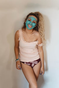 Portrait of beautiful young woman standing against white wall