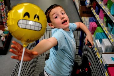 Portrait of boy holding toy while sitting in shopping cart