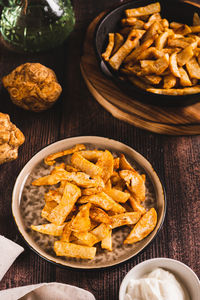 Fried celery root on a plate and sauce in a bowl on the table vertical view