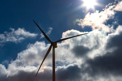 Low angle view of wind turbine against cloudy sky