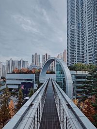 High angle view of elevated walkway leading towards buildings in city against sky