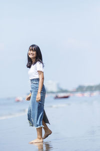 Full length of girl standing at beach against sky