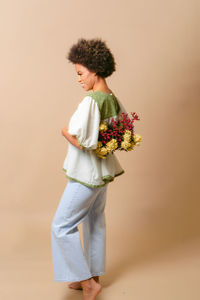 Side view of young woman standing against white background