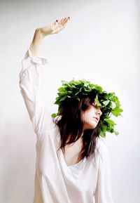 Young woman wearing leaves against white background