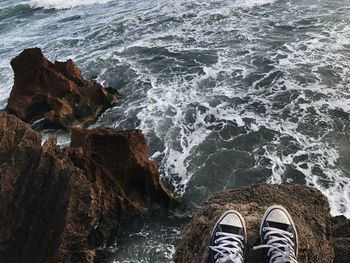 Low section of person standing on rocky shore