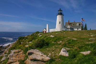 Lighthouse by sea against sky
