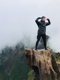 Man standing on rock against sky