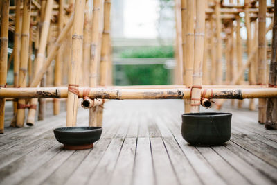 Close-up of bowls on floorboard by bamboos