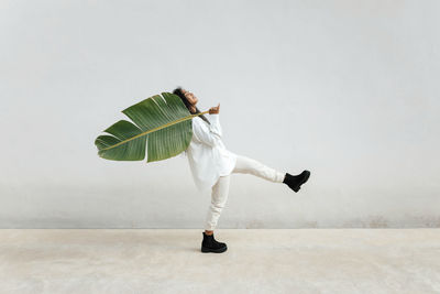 Side view of woman dancing against white background