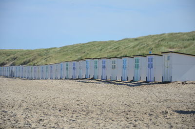 Beach huts in row against clear blue sky