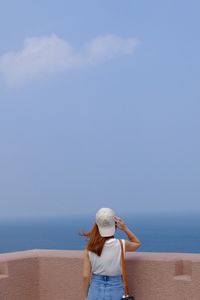 Woman standing by sea against sky