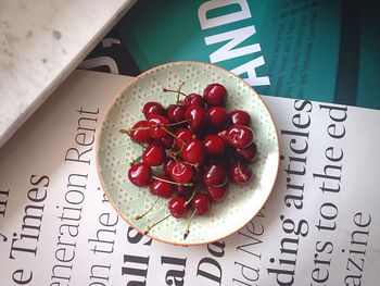 Directly above shot of cherries in plate on book