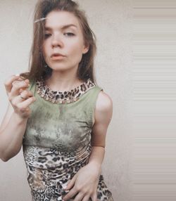 Portrait of a beautiful young woman standing against wall