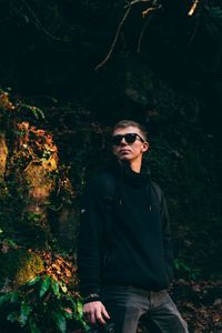 Young man wearing sunglasses standing in forest