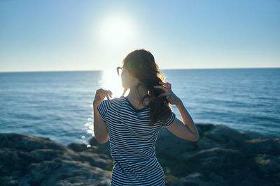 Woman standing at sea shore against sky