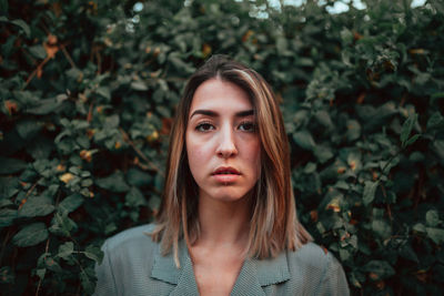 Portrait of young woman standing against plants