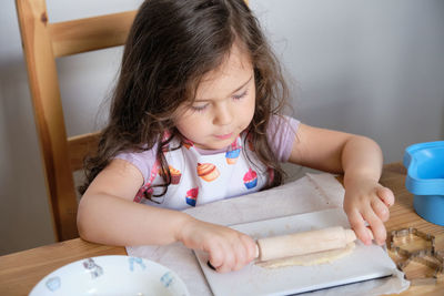 A young girl is playing chef at the kitchen table.