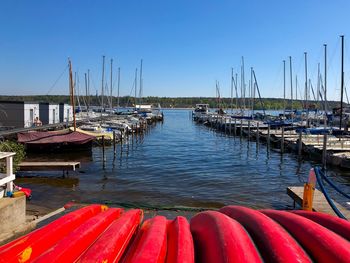 Sailboats moored in harbor against clear blue sky