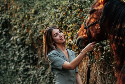 Young woman with horse standing outdoors