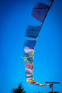 Low angle view of prayer flags hanging against clear blue sky