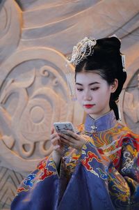 Woman looking at camera while using mobile phone