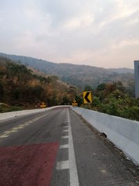 Road sign by mountain against sky