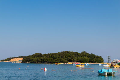 Sailboats in sea against clear blue sky