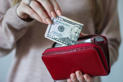 Midsection of woman holding currency and purse at home