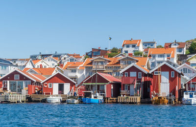 Buildings by houses against clear blue sky