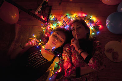 Young women illuminated by string lights