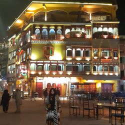 People in restaurant by illuminated city at night