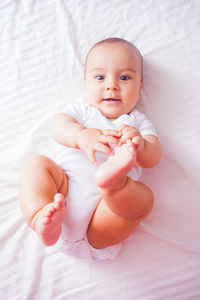 High angle view of cute baby lying on bed