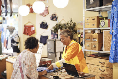 Saleswoman assisting female customer at checkout counter in store