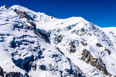 Scenic view of snowcapped mountains against clear blue sky