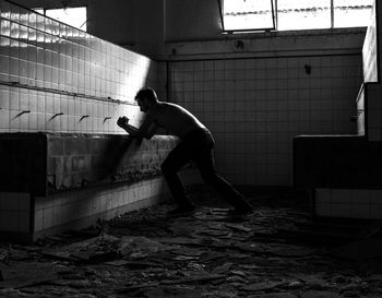 Side view of shirtless man standing at abandoned building