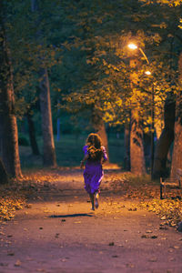 Rear view of woman running in park barefoot in autumn 