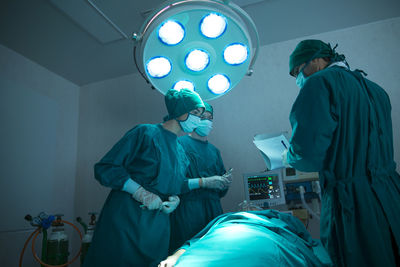 Doctors discussing while performing surgery over patient