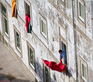 High angle view of man drying red sheet on window